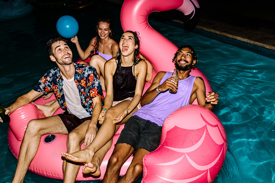 Eine Gruppe jugendlicher treibt auf einem pinken Flamingo im Schwimmbecken
